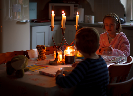Two children in a table lit by only a candle